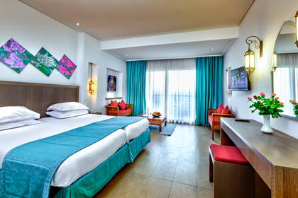 Pokój hotelowy z łóżkiem, biurkiem i zasłonami.