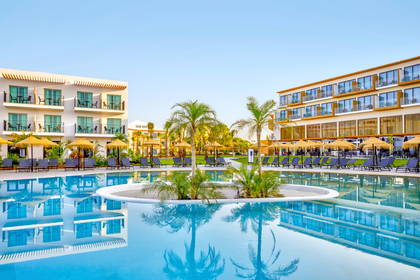 Kompleks hotelowy z basenem i palmami.