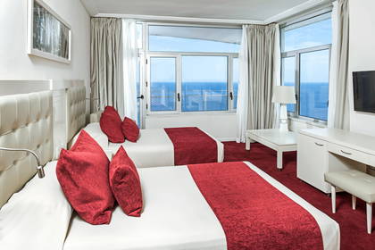 Pokój hotelowy z dwoma łóżkami i widokiem na morze.
