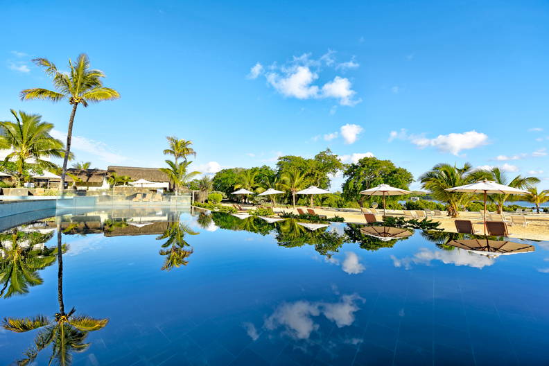 Błękitny basen, palmy i leżaki w tropikalnym kurorcie.