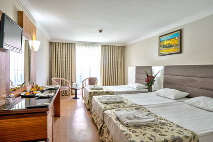 Pokój hotelowy z trzema pojedynczymi łóżkami i toaletką.