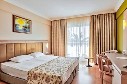 Pokój hotelowy z dużym łóżkiem, biurkiem i oknem.