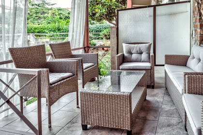 Patio z meblami z wikliny i szklanym stolikiem.