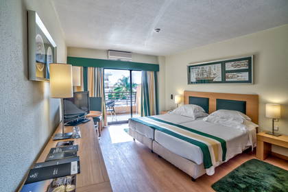 Pokój hotelowy z łóżkiem, biurkiem i balkonem.