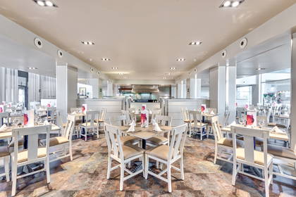 Wnętrze restauracji. Nakryte stoły i białe krzesła.