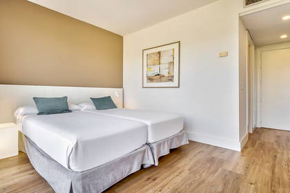 Pokój hotelowy z dwoma łóżkami i drewnianą podłogą.