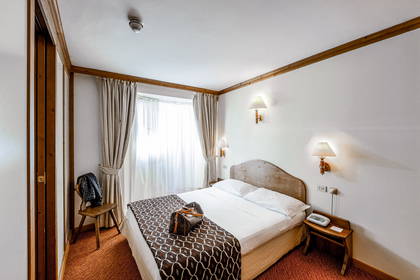 Pokój hotelowy z łóżkiem, zasłonami i torbą.