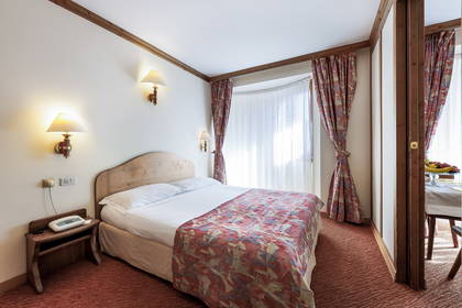 Pokój hotelowy z łóżkiem, szafką nocną i zasłonami.