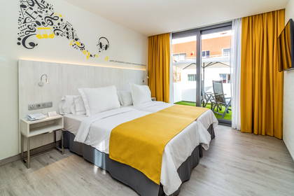 Pokój hotelowy z dwoma łóżkami, balkonem i motywem muzycznym.