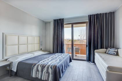 Jasny pokój hotelowy z balkonem, łóżkiem i kanapą.