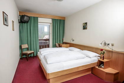 Pokój hotelowy z łóżkiem, balkonem i telewizorem.