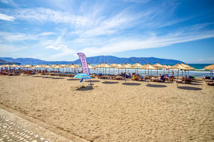 Plaża z parasolami i leżakami w słoneczny dzień.