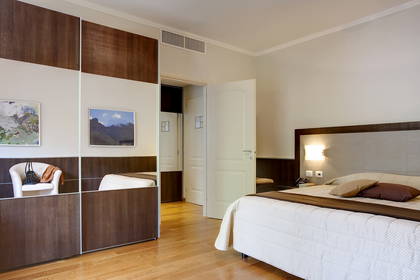 Pokój hotelowy z dużym łóżkiem i szafą z lustrzanymi drzwiami.