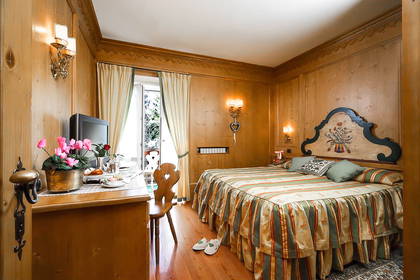 Drewniany pokój hotelowy z łóżkiem, biurkiem i balkonem.