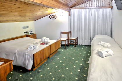 Pokój hotelowy z dwoma łóżkami i drewnianym sufitem.