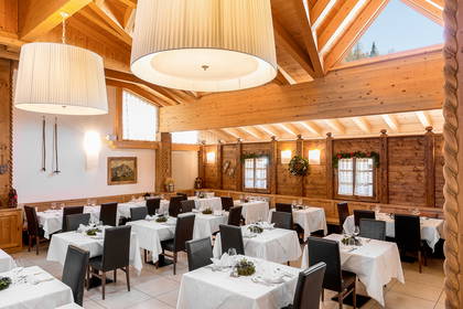 Restauracja z drewnianym wystrojem, nakrytymi stołami i dużymi lampami.
