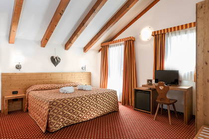 Pokój hotelowy z łóżkiem, biurkiem i drewnianym stropem.