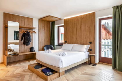 Pokój hotelowy z łóżkiem, szafą i balkonem.