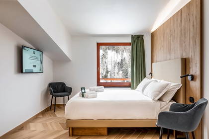 Pokój hotelowy z dużym oknem i widokiem na las.