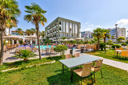 Basen hotelowy z palmami i stolikami.
