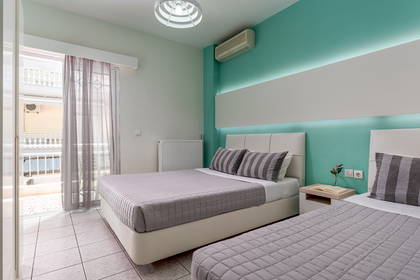 Pokój hotelowy z balkonem, dwa łóżka i turkusowa ściana.