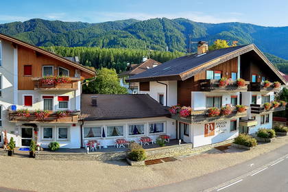 Hotel w górach z balkonami ozdobionymi kwiatami.
