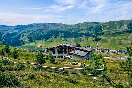 Górski krajobraz z budynkiem na tle zielonych wzgórz.