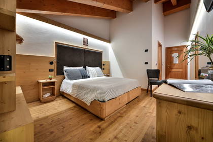 Pokój hotelowy z drewnianą podłogą, łóżkiem i drewnianymi belkami stropowymi.
