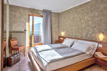 Pokój hotelowy z dwoma łóżkami, balkonem i walizką.
