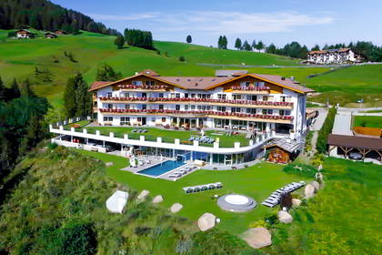 Luksusowy hotel z basenem na tle zielonych wzgórz.