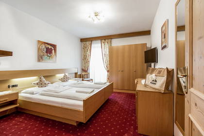 Pokój hotelowy z drewnianym łóżkiem i czerwonym dywanem.