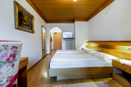 Pokój hotelowy z drewnianym sufitem, łóżkiem i telewizorem.
