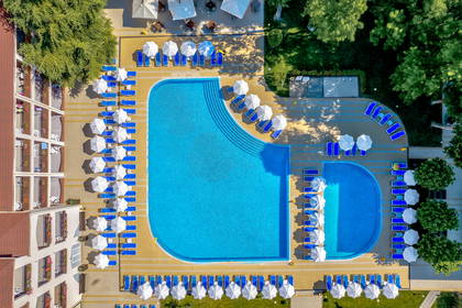 Widok z góry na hotelowy basen z leżakami i parasolami.