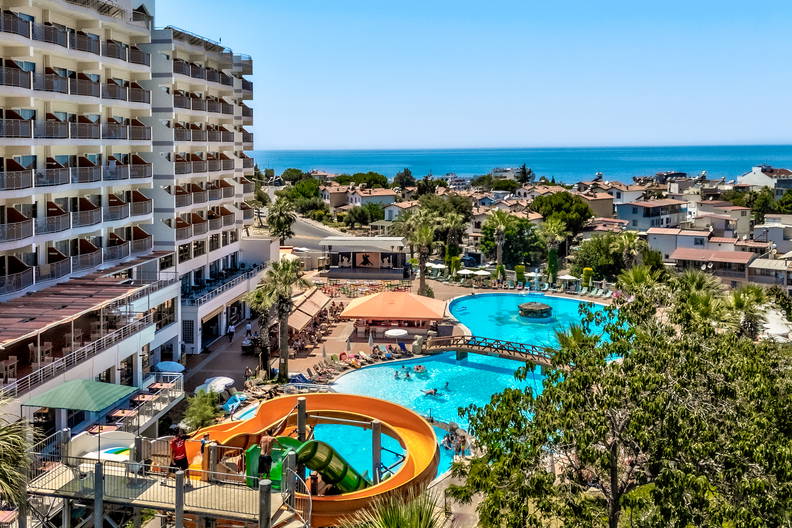 Hotel z basenem i zjeżdżalnią, morze w tle.