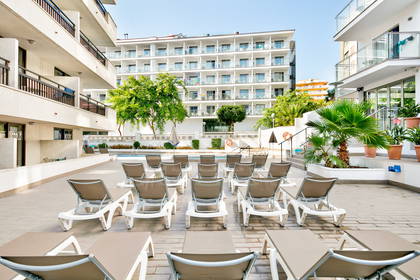 Basen hotelowy z leżakami w słoneczny dzień.