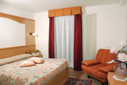 Pokój hotelowy z łóżkiem, zasłonami i krzesłem.