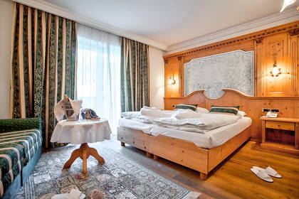 Pokój hotelowy z drewnianym łóżkiem, stolikiem i zasłonami w oknach.