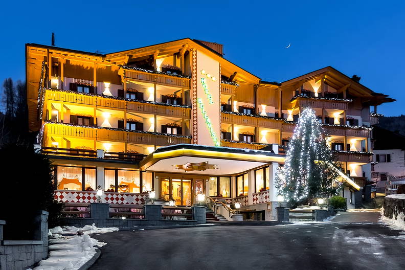 Oświetlony hotel Bellavista z choinką w nocy.