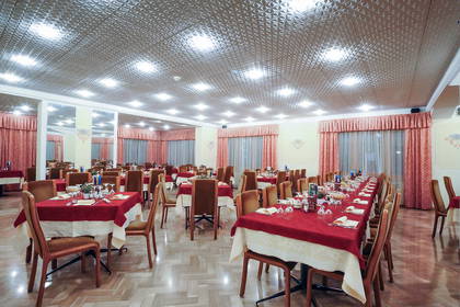 Sala restauracyjna z nakrytymi stołami i krzesłami.