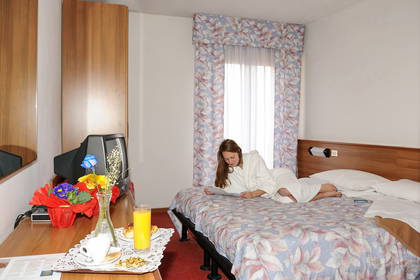 Kobieta w szlafroku czyta książkę w pokoju hotelowym.