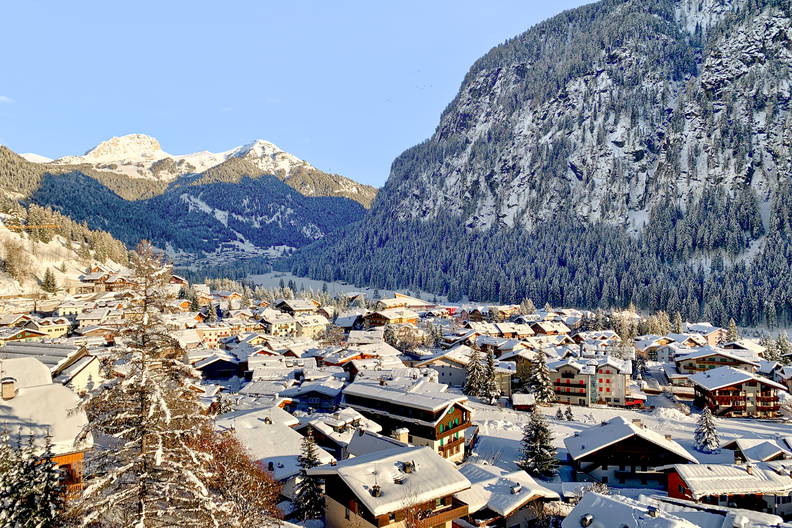 Miasteczko w górach zimą. Budynki i drzewa pokryte śniegiem.