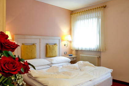 Pokój hotelowy z łóżkiem, kwiatami i oknem.