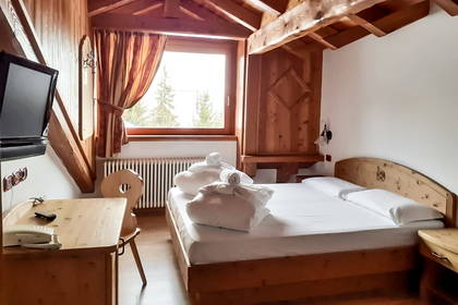 Pokój hotelowy z drewnianym wykończeniem. Widoczne łóżko, biurko i okno.