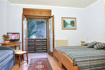 Pokój hotelowy z balkonem i widokiem na las.