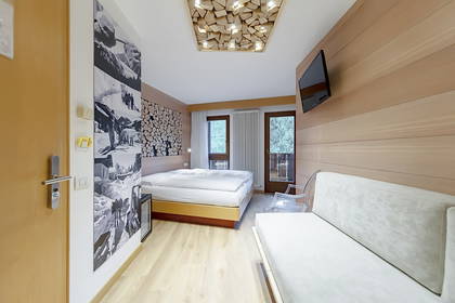 Jasny pokój hotelowy z łóżkiem, sofą i designerskimi lampami.