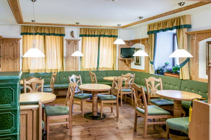 Wnętrze restauracji z drewnianymi meblami i zieloną tapetą.
