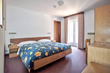 Pokój hotelowy z łóżkiem, szafką i biurkiem.