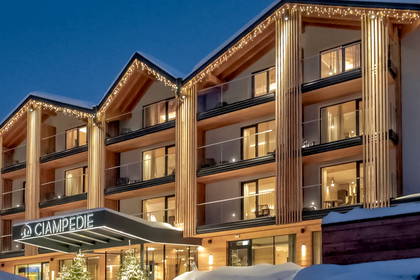 Oświetlony zimowy hotel "Ciampedie" i choinki pokryte śniegiem.