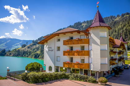 Hotel nad jeziorem w górach w słoneczny dzień.