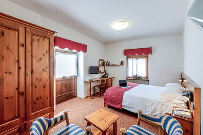 Pokój hotelowy z łóżkiem, biurkiem i drewnianą szafą.